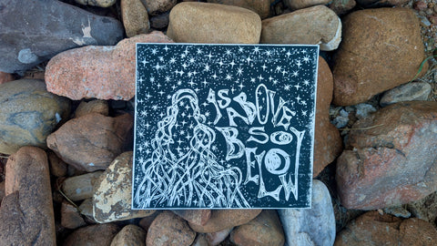 As Above, So Below — Black & White Linocut Print featuring intricate celestial and root imagery with stylized white lettering on black watercolor paper, embodying dark feminine aesthetic.