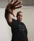 Man wearing a black premium heavyweight fabric t-shirt with colorful symbolic eye graphics, extending his hand forward, showcasing the All Eyes On Me Tee.