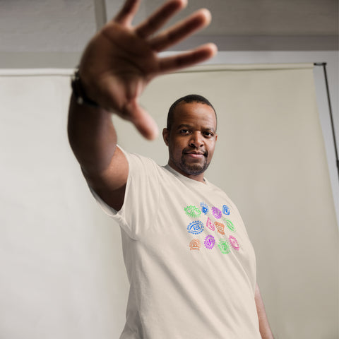 Man wearing a premium heavyweight solid color All Eyes On Me Tee with colorful eye symbols printed on the front, reaching hand toward the camera against a neutral background