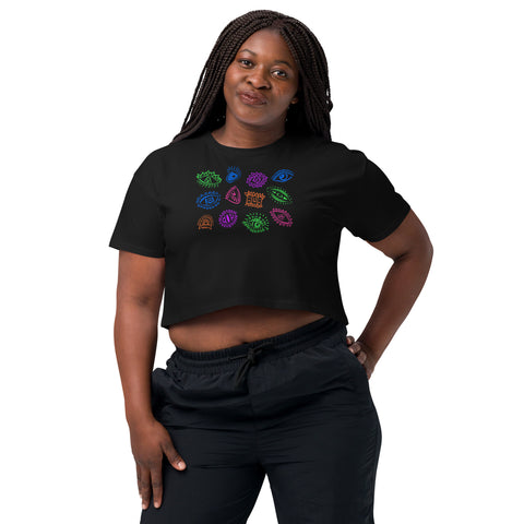 Woman wearing a black "All Eyes on Me Crop Top" featuring colorful, mystical eye symbols in a relaxed fit with cropped length, styled with black pants.