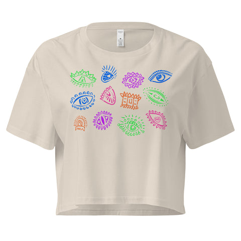 Beige lightweight All Eyes on Me Crop Top featuring colorful, whimsical eye illustrations in shades of green, blue, pink, purple, and orange, designed with a relaxed, cropped fit.