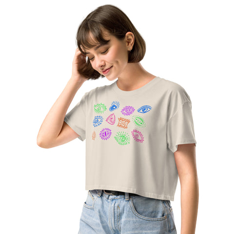 Woman wearing a relaxed fit, lightweight All Eyes on Me Crop Top in soft beige featuring colorful symbolic eye illustrations, paired with casual light-wash jeans.