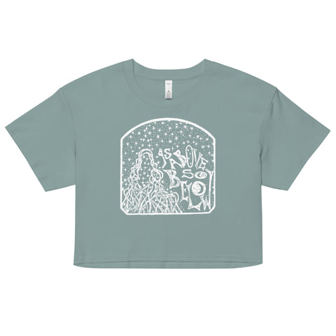 As Above, So Below Crop Top (White) in soft, lightweight combed cotton with a relaxed, cropped fit featuring a mystical white graphic of stars and flowing lines on a muted sage green background.